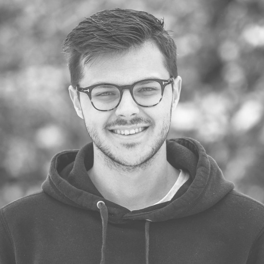 Smiling man wearing glasses and hoodie outdoors