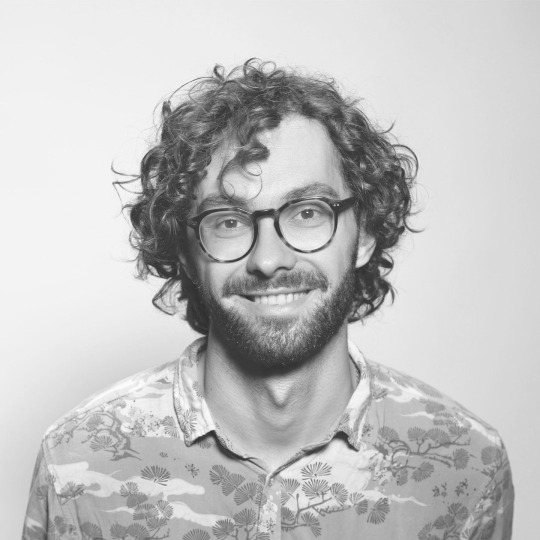Smiling man with curly hair and glasses