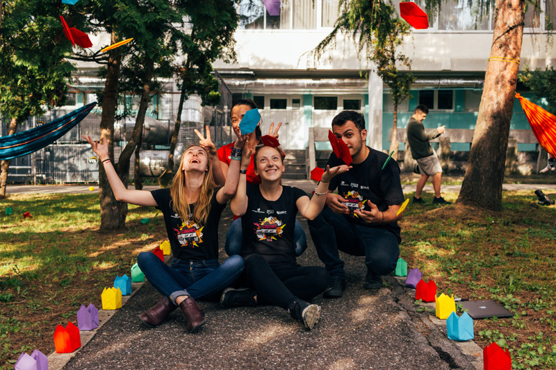 Friends tossing colorful paper shapes outdoors